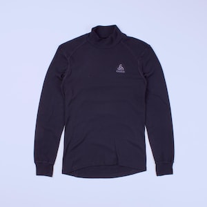 Puede incluir: Camiseta de manga larga azul marino oscuro con cuello alto. La camiseta tiene un pequeño logotipo en el pecho. Los puños y el cuello son acanalados. La camiseta está hecha de un material suave y cómodo.