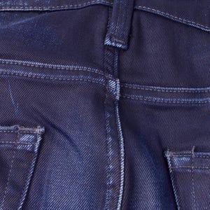 May include: Close-up of the back of dark blue denim jeans. The image highlights the details of the pockets, stitching, and belt loops. The denim has a slightly faded appearance, with visible wear and tear.