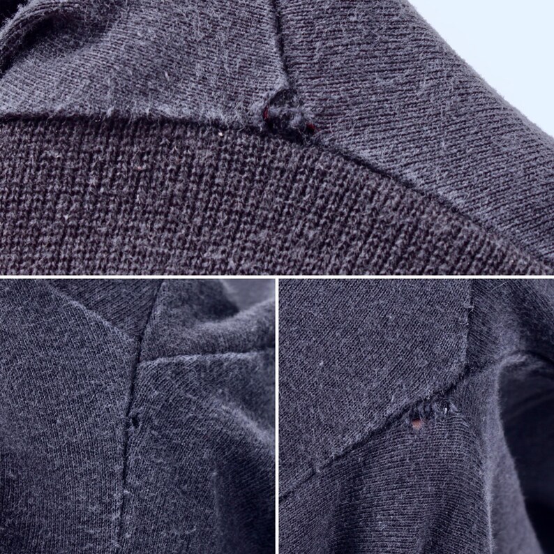 May include: Close-up of dark gray fabric with visible stitching and small imperfections. The image shows the texture and construction of the material, highlighting the details of the garment's seams and potential wear.