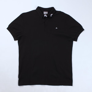 May include: Black polo shirt with short sleeves and a button-down collar. The shirt has a small white logo on the chest and a larger white design on the collar. A classic, casual top for everyday wear.