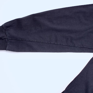May include: Close-up of a dark navy blue long sleeve shirt sleeve. The sleeve has a ribbed cuff and a seam running down the length of the arm. The fabric appears to be a soft, durable material.