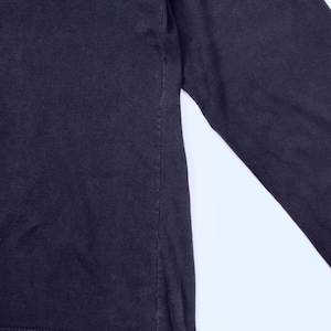 May include: A close-up of a black long-sleeve shirt. The shirt is made of a soft material and has a simple design. The sleeve is visible on the right side of the image.