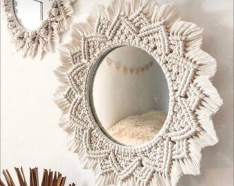 May include: Two round mirrors with a macrame frame. The larger mirror has a white macrame frame with a fringe border. The smaller mirror has a white macrame frame with a more intricate design.