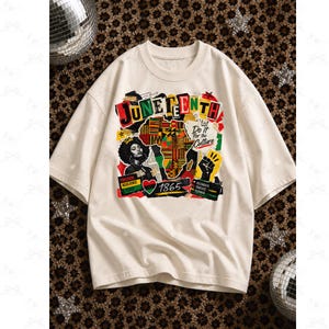 May include: Cream-colored Juneteenth t-shirt with a colorful graphic. The design includes the word "Juneteenth" in bold letters, a map, a portrait of a woman, and the text "Do it for the Culture". The shirt also features the year "1865".