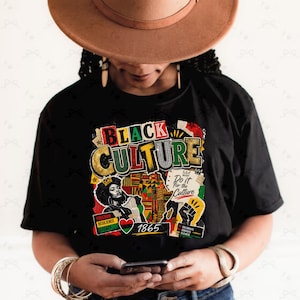 Op de afbeelding: Zwart T-shirt met een kleurrijk grafisch ontwerp met de tekst "BLACK CULTURE" in goud, groen en rood. Het ontwerp bevat een illustratie van een vrouw, een hart en de tekst "1865".