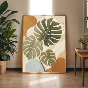 Könnte beinhalten: Ein rechteckiger gerahmter Wandkunstdruck mit drei großen, dunkelgrünen Monstera-Blättern als zentrales Motiv. Der Hintergrund besteht aus abstrakten Formen in gedämpftem Terrakotta, sanftem Beige und Hellblau, akzentuiert durch feine Linien.