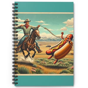 Può includere: Quaderno a spirale con un'illustrazione umoristica di un cowboy a cavallo che cerca di catturare un hot dog gigante. Lo sfondo presenta un paesaggio desertico con montagne e cielo blu. Il quaderno ha una copertina turchese.