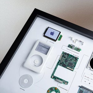 May include: A disassembled white first-generation iPod with its components laid out on a white surface. The components include the LCD screen, click wheel, logic board, headphone jack, and hard drive.
