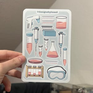Könnte beinhalten: Ein Bogen Aufkleber mit verschiedenen Laborgeräten, darunter Bechergläser, Reagenzgläser, Pipetten und Schutzbrillen. Die Aufkleber befinden sich auf einem hellgrauen Hintergrund mit dem Text "@designsbylexed" oben.