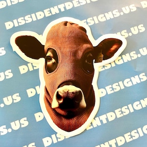 May include: A brown cow wearing a red ski mask. The cow is looking directly at the camera. The image is a sticker with a white border.
