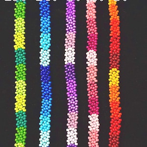May include: Five beaded lanyards in a row, each a different color. The colors are green, blue, purple, pink, and orange. Each lanyard has a gold clasp at the top and is made of small, round beads. Numbers are printed above each lanyard.
