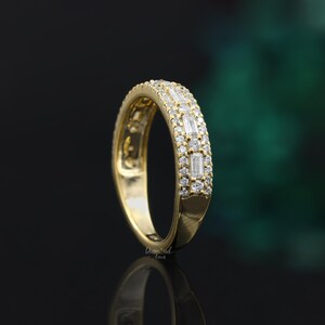 May include: A gold band ring with a row of baguette-shaped diamonds and a row of round diamonds.