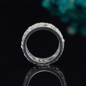 Pode incluir: Um anel de banda de prata com uma fileira de pequenos diamantes redondos engastados em pav&eacute;. O anel &eacute; mostrado de lado, com os diamantes voltados para o espectador.