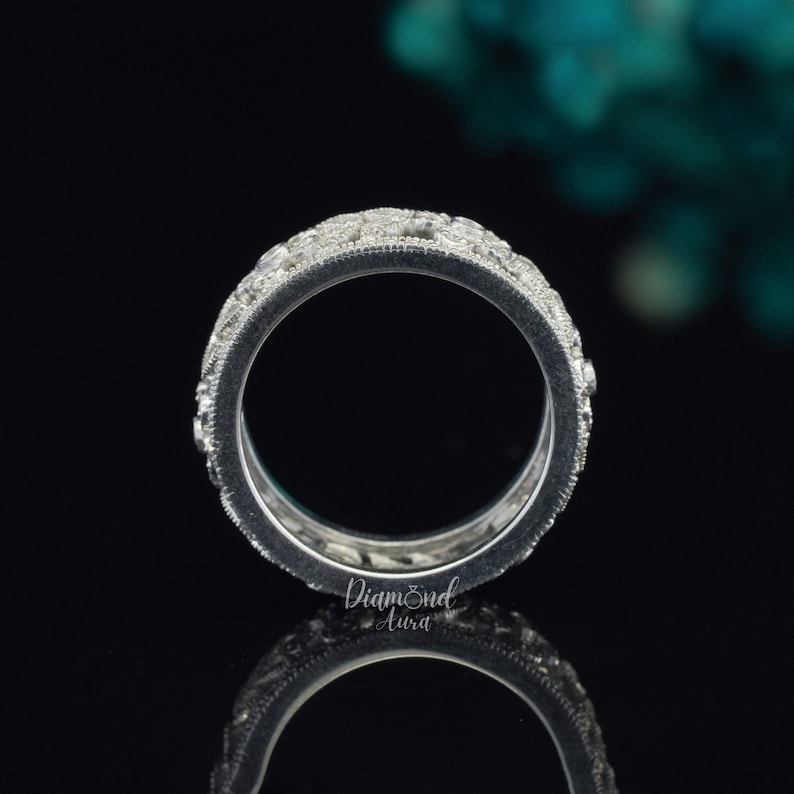 Pode incluir: Um anel de banda de prata com uma fileira de pequenos diamantes redondos engastados em pav&eacute;. O anel &eacute; mostrado de lado, com os diamantes voltados para o espectador.
