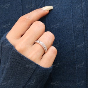 May include: A delicate, double-row diamond eternity band ring with a rose gold setting. The ring features a row of baguette-shaped diamonds and a row of round brilliant diamonds.