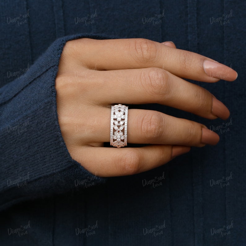 Pode incluir: Um anel de prata com um design floral cravejado com pequenos diamantes. O anel &eacute; usado no dedo de uma pessoa.