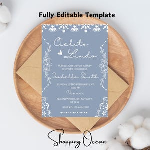 Könnte beinhalten: Eine blaue Babyparty-Einladung mit weißen Spitzenbesatz und floralen Akzenten. Der Text lautet "Cielito Lindo" und enthält den Namen "Isabella Smith", Datum, Uhrzeit und Veranstaltungsort.