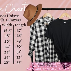 May include: A size chart for a Bella + Canvas unisex t-shirt, with measurements in inches. A black t-shirt, a black and white plaid shirt, and a brown hat are displayed on a clothing rack. The chart includes sizes XS to 3XL.