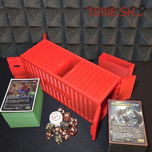 Può includere: Un porta carte rosso a forma di container con la scritta "TENESKY" sul lato. Il supporto è aperto, rivelando due scomparti. Una pila di carte verdi, dadi e due mazzi di carte sono accanto al supporto.