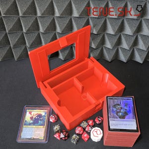 Può includere: Una scatola rossa aperta per riporre giochi di carte con scomparti interni. Sono visibili dadi, una carta in una custodia e un mazzo di carte. Il testo "TENE.SK" è visibile sullo sfondo.