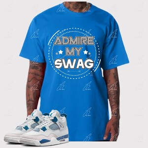 May include: A blue t-shirt with the text "ADMIRE MY SWAG" in a white and gray design. The image also features a pair of white and blue sneakers.