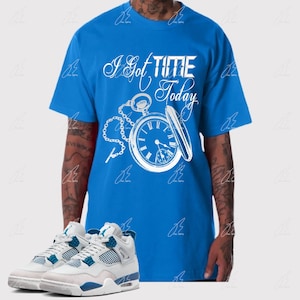 May include: A blue t-shirt with a white pocket watch graphic and the text "I got TIME Today". The model is wearing white and blue sneakers.