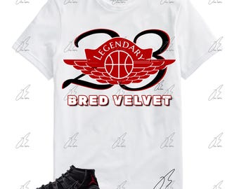 May include: White t-shirt with a red and black graphic of a basketball shoe with the text "LEGENDARY 23 BRED VELVET". A pair of black and red basketball shoes are shown below the t-shirt.