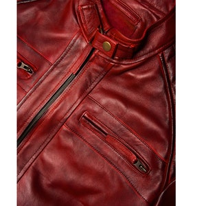 May include: A close-up of a red leather jacket with a zipper closure and multiple pockets. The jacket has a quilted design on the shoulders and a stand-up collar.