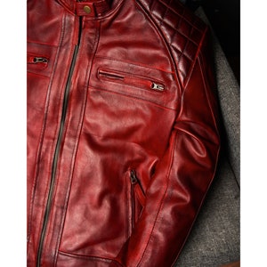 May include: A close-up of a red leather jacket with quilted shoulders and zippered pockets.