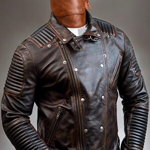 May include: A brown leather jacket with a zip fastening and a distressed look. The jacket has a stand-up collar and a quilted design on the sleeves.