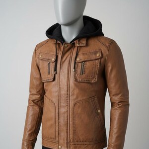 May include: A brown leather jacket with a black hooded lining. The jacket features two chest pockets with zippers, two lower pockets, and a front zipper closure. The jacket is displayed on a mannequin.