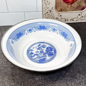 Peut inclure: Bol en céramique blanc et bleu avec un bord argenté. Le bol présente un motif classique bleu et blanc de type Willow. Le bol est rond et semble être vintage ou antique.