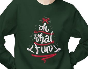 May include: A dark green sweatshirt with a Christmas tree design. The tree is made of white and red lettering that says "oh what fun". A red bow is at the top of the tree.