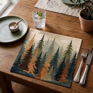 Pode incluir: Um lugar americano quadrado de tecido com uma paisagem florestal impressa, apresentando árvores perenes altas em tons de verde escuro, azul marinho e laranja dourado sobre um fundo bege claro, criando uma cena de bosque com acabamento fosco.