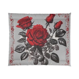 May include: A gray pillow with a red rose pattern. The roses are in full bloom and have dark green leaves. The pillow has a white border with a red floral pattern.