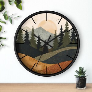 May include: A round wall clock with a black frame. The clock face features a landscape scene with mountains, trees, and a setting sun in shades of green, orange, and beige. The clock hands are black.