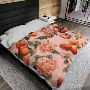 May include: A pink and white bedding set with a peach floral pattern. The bedding features a repeating pattern of peaches and pink flowers on a light pink background.