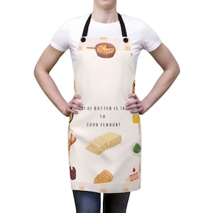 May include: A white apron with a checkered border and a variety of butter-themed illustrations, including a stick of butter, a pat of butter, a croissant, and a slice of cake. The text "A Taste of Butter is the Key to Good Flavor!" is printed on the apron.