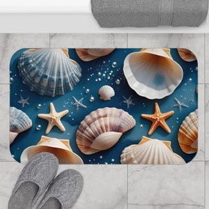 May include: A rectangular bath mat featuring a blue background with seashells and starfish. The seashells are in shades of white, tan, and blue. The starfish are orange. Gray slippers are at the bottom left.