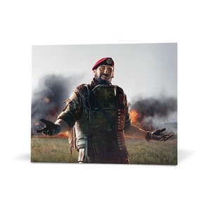May include: A man in a red beret and camouflage uniform stands with his arms outstretched, smiling. He is wearing a tactical vest with ammunition pouches and a red bandana. The background is a blurry image of an explosion with smoke and fire.