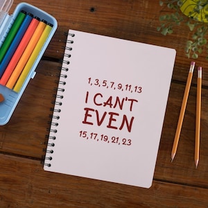 May include: A white spiral-bound notebook with the dark red text "1, 3, 5, 7, 9, 11, 13 I CAN'T EVEN 15, 17, 19, 21, 23" printed on the cover, accompanied by a light blue plastic pencil case containing five colored markers and two yellow pencils.