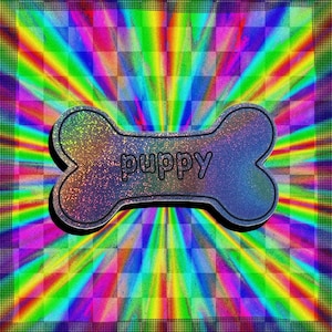 May include: A dog bone-shaped design with the word "puppy" in the centre. The bone is a gradient of blue, purple, and gold with a glittery texture. The background is a vibrant, colourful pattern of rainbow stripes and checkered squares.