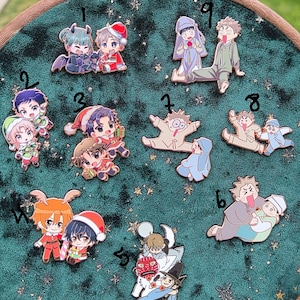May include: A collection of colorful enamel pins featuring anime-style characters. The pins are set against a dark green, star-speckled background. The characters are depicted in various poses and outfits, including holiday-themed attire.