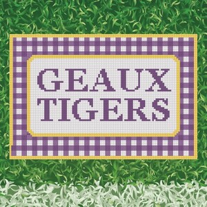 May include: A rectangular cross-stitch pattern featuring a purple and white gingham border with a yellow trim. The center is white with the purple text GEAUX TIGERS in a block font. The design is presented against a green grass background.