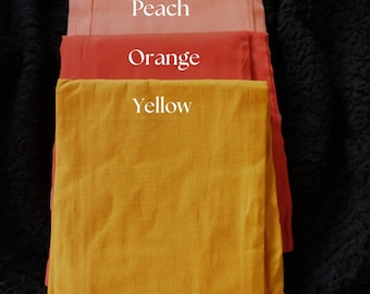 May include: A stack of folded fabric in shades of purple, peach, orange, and yellow. The word "Purple", "Peach", "Orange", and "Yellow" are written on each fabric. The brand name "Prisha" is written on the bottom yellow fabric.