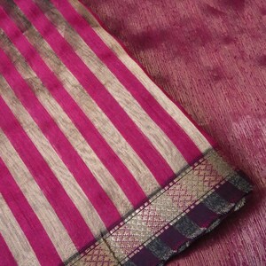 May include: Close-up of a fabric with vertical stripes in shades of pink and beige. The fabric has a decorative border with gold and dark purple accents. The word "Prisha" is visible in white text.