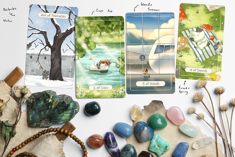 Puede incluir: Cartas del tarot con ilustraciones de gatos en escenas de invierno, verano y primavera, junto con gemas coloridas y flores secas. Las cartas incluyen 'Ace of Pentacles', '2 of Cups', '3 of Wands' y '4 of Swords'.