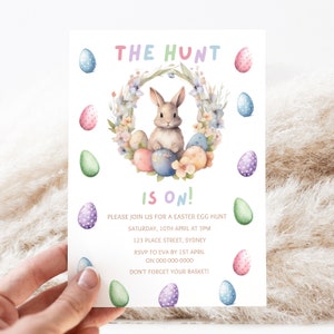 May include: An Easter egg hunt invitation with a watercolor illustration of a bunny rabbit sitting in a wreath of flowers and eggs. The text reads "The Hunt is On!" with details about the event, including the date, time, location, RSVP information, and a reminder to bring a basket.