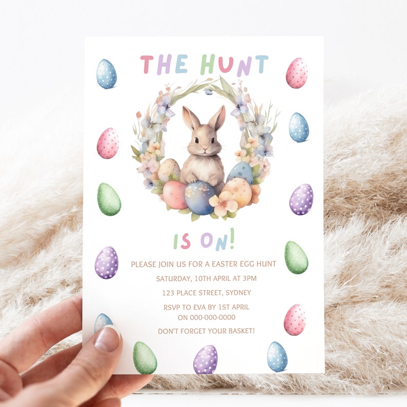 May include: An Easter egg hunt invitation with a watercolor illustration of a bunny rabbit sitting in a wreath of flowers and eggs. The text reads "The Hunt is On!" with details about the event, including the date, time, location, RSVP information, and a reminder to bring a basket.