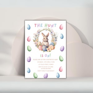 May include: An Easter egg hunt invitation with a watercolor illustration of a bunny rabbit sitting in a wreath of flowers and colorful eggs. The text reads "The Hunt is On!" with details about the event, including the date, time, location, and RSVP information.